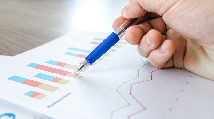 A hand holding a pen on a sheet with different graphs