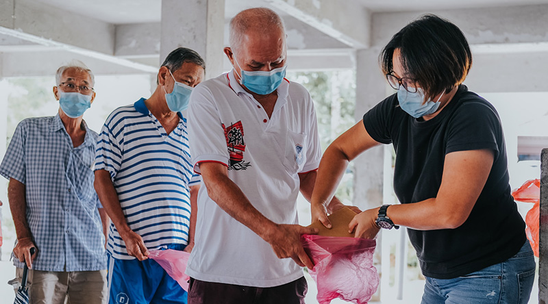 Woman with black hair giving food to elder men