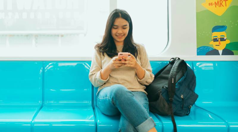 A woman looking at her phone while in the metro